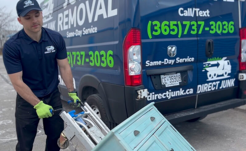 Crew member moving a blue cabinet on a dolly