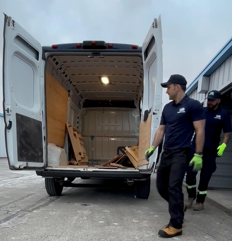 Direct Junk crew lifting heavy furniture into the truck during junk removal